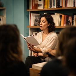 Zami Benalli leyendo un fragmento de poesía frente a una pequeña audiencia